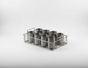 Stainless steel wire basket holding eight cylindrical metal cups arranged in two rows of four, on a grey gradient background
