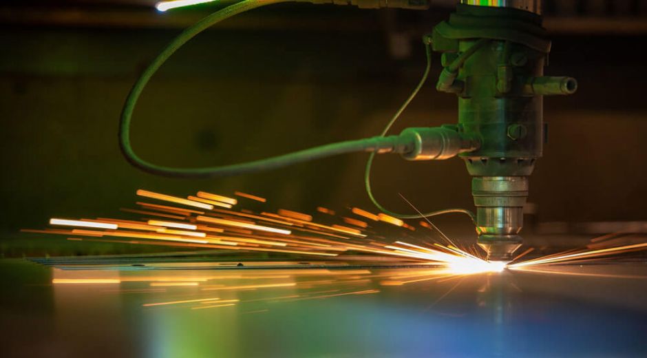 Laser cutting machine cutting metal with sparks flying.