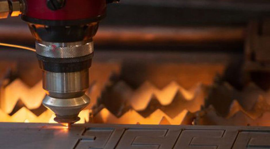 tube-laser-cutting-services Close-up of a laser cutting head cutting a metal tube.